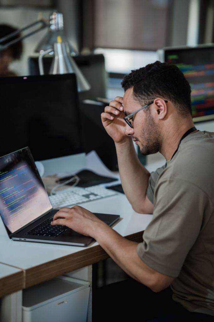 man thinking and typing on laptop